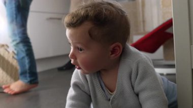 Bebek mutfakta yerde oturuyor. Oyun zamanı şaşırmış ve anlamlı görünüyor. Aile evinde heyecan verici bir keşif ve duygu anı.