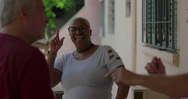 Yaşlı bir adam, neşeli bir zenci kadın ve genç bir adam canlı bir açık hava toplantısında dans ediyorlar, çeşitlilik, neşe ve toplumsal bağ sergiliyorlar.