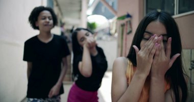 Gençler sıkıntı içinde yüzlerini kapatırken, banliyö sokaklarında arkadaşlar gülüyor, gençlerin zorbalıklarını, akran ilişkilerini ve duygusal zorlukları temsil ediyorlar.