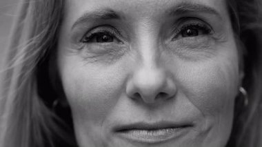 Orta yaşlı kadın gözlerinin yakın plan portresi. Sakin ve içerik ifadesi, ince çizgiler ve ayrıntılar. İçtenlik ve özgünlüğü siyah ve beyaz olarak aktarıyor..