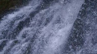 Çapraz beyaz su akışı Ultra yavaş çekimde düz kayadan aşağı akıyor. Yüksek hızlı kamerayla çekiliyor.