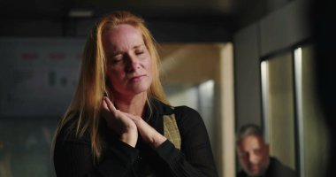 Ofiste duygusal hassasiyet gösteren sarışın bir iş kadını, gözleri kapalı ve elleri yoğun bir üzüntü anında sıkışık durumda.