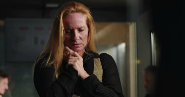 Ofiste duygusal hassasiyet gösteren sarışın bir iş kadını, gözleri kapalı ve elleri yoğun bir üzüntü anında sıkışık durumda.