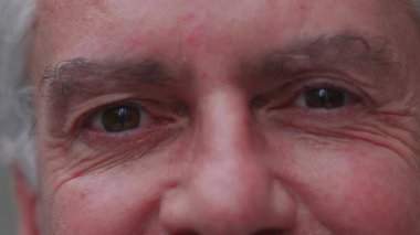 Makro yakın plan erkek yüzü, görünür kırışıklıklar ve anlamlı gözler, ince neşe ve doğal sıcaklığı gerçek ifade yoluyla gösteriyor..