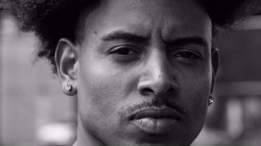 Afrika kökenli genç bir Amerikalı 'nın yakın plan portresi. Yoğun ve ciddi bakışları var. İfadesinde ince bir gerilim var..