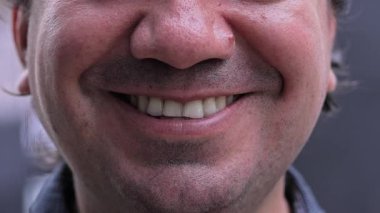 Kısa kesimli sakallı, kendine güvenen, geçmişi bulanık gülümseyen adamın yakın çekimi.