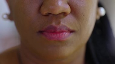 Makro, Afrikalı Amerikalı kadınların dudaklarını tarafsız ifadeyle kapatıyoruz. Doku, dişilik ve sessiz iç gözlem gösteren detaylı bir portre..