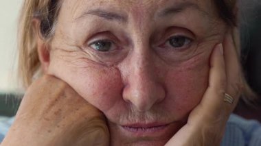 Yaşlı kadın doğrudan kameraya bakıyor. Yumuşak, bitkin bakışlarla. Detaylı olarak yakından bakınca yaş, esneklik ve yaşam tecrübesi gösteriyor.