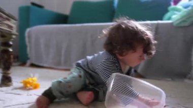 Oyuncu çocuk evin zemininde enerjik bir merakla sürünüyor, uzayı keşfediyor ve kararlı, neşeli ileri hareketiyle erken hareketliliğini gösteriyor.