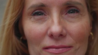 Kameraya bakan orta yaşlı bir kadının yakın plan portresi. Cilt dokusu, göz makyajı ve bakışlarındaki ince duyguları gösteriyor.