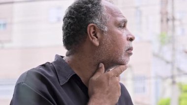 Kaybolmuş bakışları olan olgun siyah bir adam hafif bir rahatsızlık ve dalgınlık anında endişe gösteriyor.