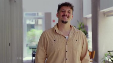 Kapalı alanda güvenle gülümseyen genç bir adam. Sıcaklık, özgünlük ve doğal ışıkta rahat bir özgüven gösteren sıradan bir portre..