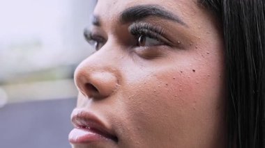 Düz saçlı, etkileyici gözlü, sakin bir ifadeyle ve yumuşak bir gülümsemeyle mesafeye bakan genç bir kadının yakın çekimi.