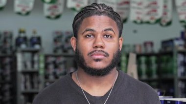 Piercing, sakal ve örgü ören genç siyahi adam portresi, modern tarzda hala ve kombinasyonlu ifade ile kameraya bakıyor..