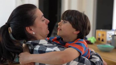 Anne oğlunu kollarında tutuyor, rahat ve samimi bir şekilde paylaşıyor. Her gün evde sıcak ve sevgi dolu bir aile ortamını paylaşıyor.