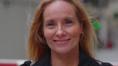 Orta yaşlı bir kadının gülümseyen portresi doğal bir ifade ve sarı saçlar, samimiyet, yakınlık ve dostça duygular gösteriyor.