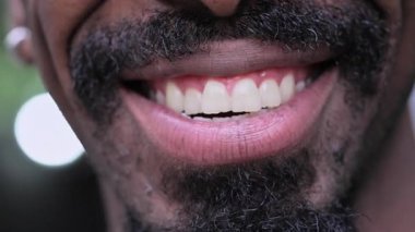 Gülümseyen siyah adamın kısa sakallı ve görünür dişli yakın çekimi neşeli bir ifade ve doğal cazibe sergiliyor.