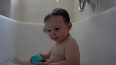 Bebek musluğa doğru tam bir ilgi ve cazibeyle uzanırken, cildindeki su damlacıkları hafif bir keşif, duyusal bağlılık ve erken gelişim merakını artırıyor.