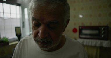Mutfaktaki yaşlı adamın içsel ifadesiyle, yalnızlığı, yaşlanmayı ve ev hayatındaki sessiz yansımaları temsil eden yakın çekimi.