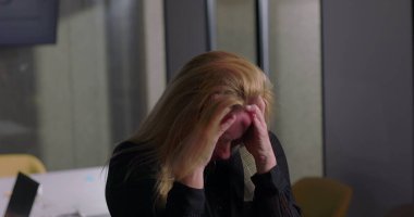 Ofis toplantısı sırasında dişlerini sıkan sarışın iş kadını, işyeri stresinin kırılma noktasına ulaşmasıyla bunalmış ve gergin.