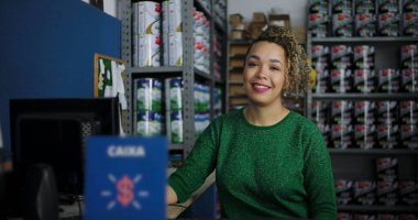 Etrafı boya ve malzemelerle çevrili bir hırdavatçıda güvenle gülümseyen genç bir kadının yakın çekimi profesyonelliği ve misafirperver bir tavrı temsil ediyor.