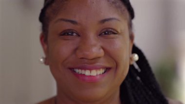 Afrika kökenli Amerikalı bir kadının samimi bir şekilde gülümseyen portresini yakın çekim, güveni, dostluğu ve gerçek mutluluğu yansıtan doğal bir ifade.