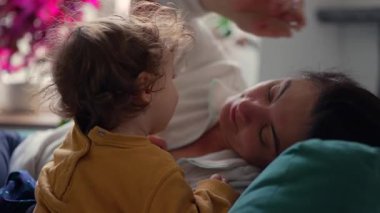 Anne, yeni yürümeye başlayan çocuk, merak uyandıran nazik jestlerle yaklaşırken huzur içinde yaslanıyor. Sıcak, güven dolu ve gevşek bir iç mekanda, aceleci olmayan bir bağ kurma çabasıyla yürekten bir değişim yaratıyor.