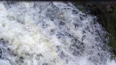 Şelale suyunun, hava ve baloncuklarla karışık, çok yavaş çekimde, yüksek hızlı bir kamerayla çekilmiş detaylı görüntüsü.