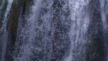 Düşen su izlerinin ve damlacıkların Ultra yavaş çekimde koyu kaya duvarına karşı yüksek hızlı kamerayla çekilmiş yakın çekimi.