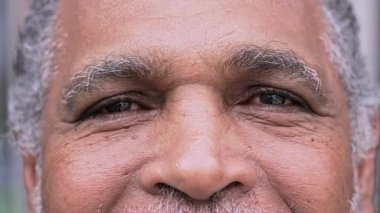 Yaşlı adamın gözlerinin, sakin ve düşünceli bir ifadeyle doğrudan kameraya baktığı yakın plan.