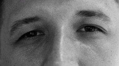 Makro, erkeklerin gözlerini siyah beyaz, sakin iç gözlem ifadeleriyle kapat. Düşünceliliği, gerçekçiliği ve duygusal derinliği ifade et..