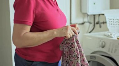 Üst düzey kadın gömleğini temiz tutuyor ve ev ortamındaki rutin ev ortamında çamaşır sepetine koyuyor..