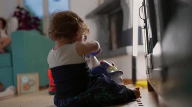 Oyuncak bir uçakla oynarken yerde rahat bir şekilde oturan bir çocuk, erken dönem yaratıcı oyun ve büyüyen bağımsız odaklanma anı oluşturur.