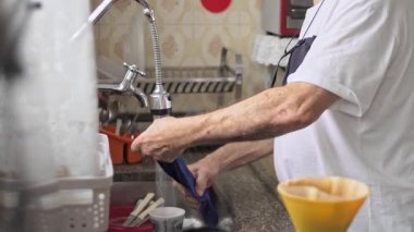 Mutfaktaki kıdemli adam, Ev Kurumu ve Günlük Sorumlulukların Bir parçası olarak Çamaşır Banyosu Yapıyor.