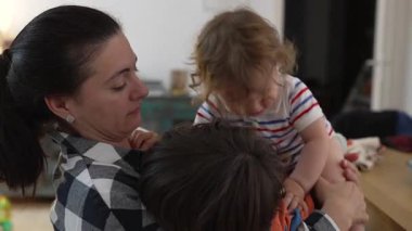 Anne kucağında yeni yürümeye başlayan çocuğu izlerken, neşeli aile anlarını paylaşıyor. Evdeki şen şakrak kaostan sonra kahkaha ve şefkat dolu.