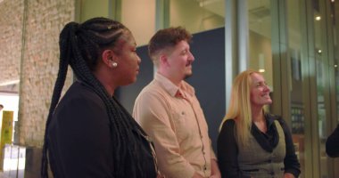 Şirket yöneticisi ofis koridorunda çeşitli takımlara hitap ediyor, parlak modern işyerindeki açık jestlerle önde gelen profesyonel sohbetler