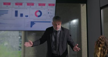 İş dünyasının kendine güvenen lideri ekranda veri tablolarıyla ilgili toplantı sırasında meşgul meslektaşlarına tutkulu bir sunum yapıyor.