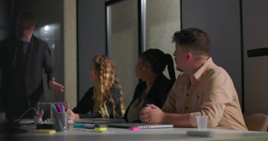 Kurum yöneticisi, kurul odasındaki renkli çizelgeler ve grafiklerle ilgili bilgileri yetkili meslektaşlarına açıklıyor. 