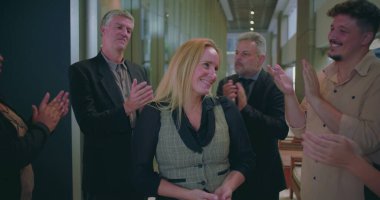 Modern ofis koridorunda bayan meslektaşlarını alkışlayan neşeli iş adamları, çeşitli iş arkadaşları başarılarını takdir ediyor ve takdir ediyorlar.