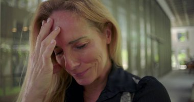 Başı öne eğik ve eli alnında, duygusal yükü ya da derin stresi ifade eden bir kadına yaklaşın.