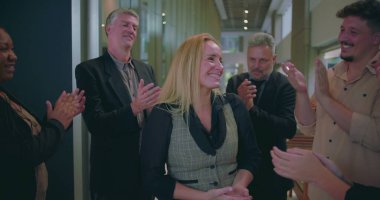 Modern ofis koridorunda bayan meslektaşlarını alkışlayan neşeli iş adamları, çeşitli iş arkadaşları başarılarını takdir ediyor ve takdir ediyorlar. 