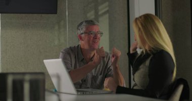 İş arkadaşları gülümser ve ofis toplantısında dostça destek anlarında el ele tutuşur, takım çalışmasını kutlar ve başarılarını paylaşırlar.