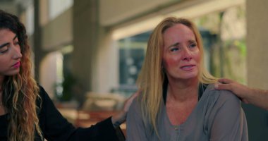 Terapi seansında grup üyeleri tarafından teselli edilen ağlayan bir kadın, acılarını dile getirirken şefkat ve destek görüyor.