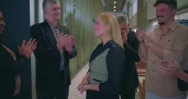 Modern ofis koridorunda bayan meslektaşlarını alkışlayan neşeli iş adamları, çeşitli iş arkadaşları başarılarını takdir ediyor ve takdir ediyorlar. 