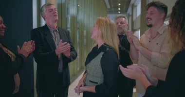 Modern ofis koridorunda bayan meslektaşlarını alkışlayan neşeli iş adamları, çeşitli iş arkadaşları başarılarını takdir ediyor ve takdir ediyorlar.