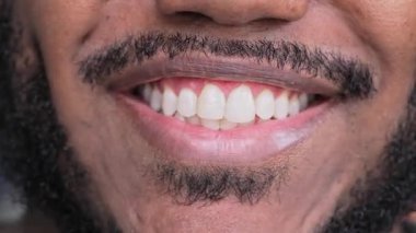 Sakallı, genç, siyah bir adamın gülümseyen ağzı. Parlak dişleri ve temiz ve doğal bir ifadeyle birlikte.