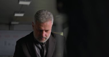 Stresli iş adamı, yüksek baskılı şirket toplantısı sırasında ofis konferans odasında tek başına dikilirken el ele vererek yüzünü kapatıyor.