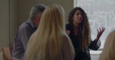 Sıkıntılı genç kadın grup terapisi sırasında acı dolu anılarını paylaştığı için ağlıyor, yaşıtları sessiz kalarak destek çemberinde şefkatli bir şekilde dinliyorlar.