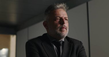 Düşünceli iş adamı, şirket toplantısında elleri çenesinde ve yoğun bakışlarıyla profesyonel kurul odasında kayboldu.