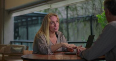 Açık ofis ortamında masadaki dizüstü bilgisayarla erkek arkadaşa kadın profesyonel açıklama fikri